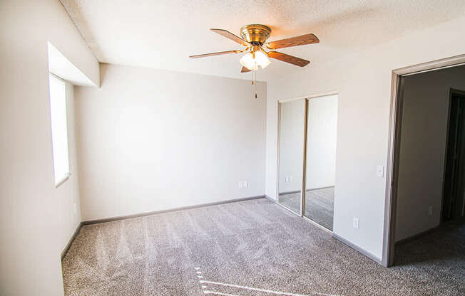 A room with a ceiling fan and carpeted floor.