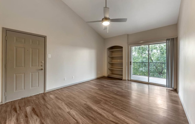 an empty living room with wood flooring and a window