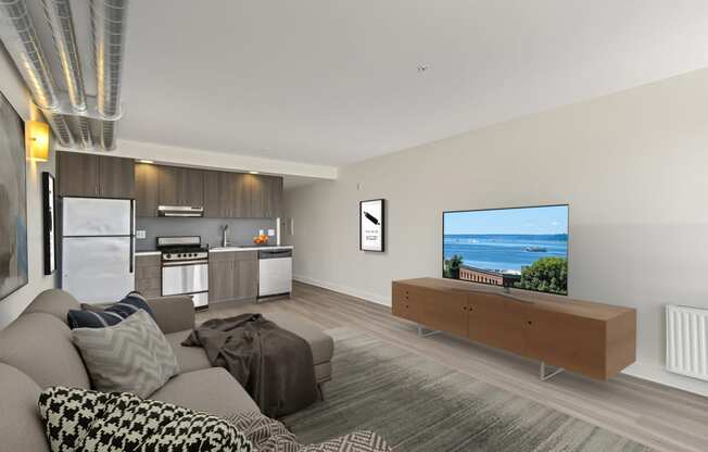 a living room with a large tv and a kitchen in the background