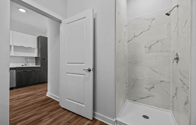A white door is in a bathroom with marble tiles.