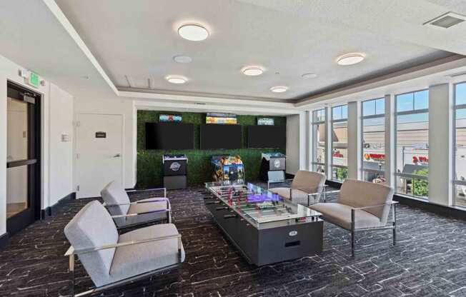 a lounge area with a table and chairs in a room with televisions