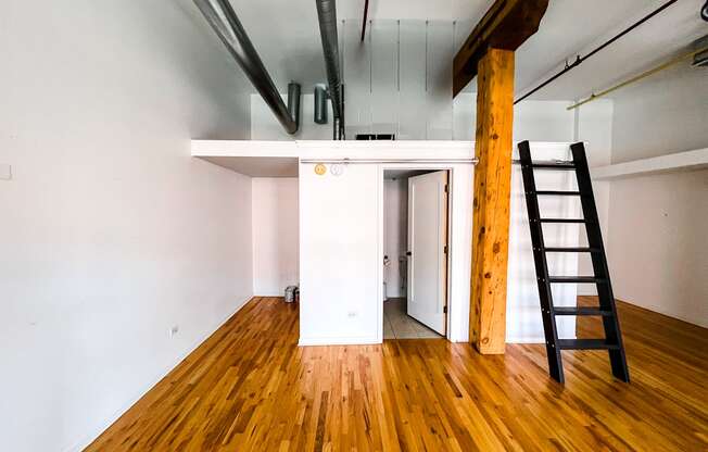 A room with wooden floors and a ladder against the wall.