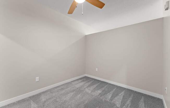 A room with a ceiling fan and a carpeted floor.