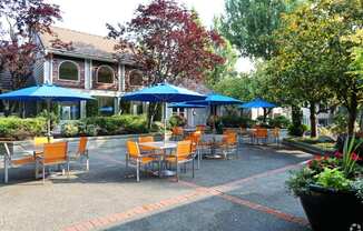 a patio with tables and umbrellas in front of a building