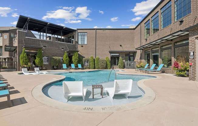 A pool with chairs around it in front of a building.