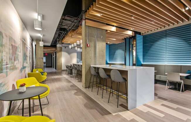 a communal area with yellow chairs and tables and a bar with blue and white walls