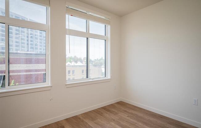 an empty room with three windows and a wooden floor