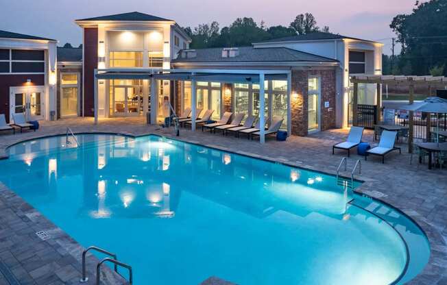 a swimming pool with lounge chairs and a building in the background