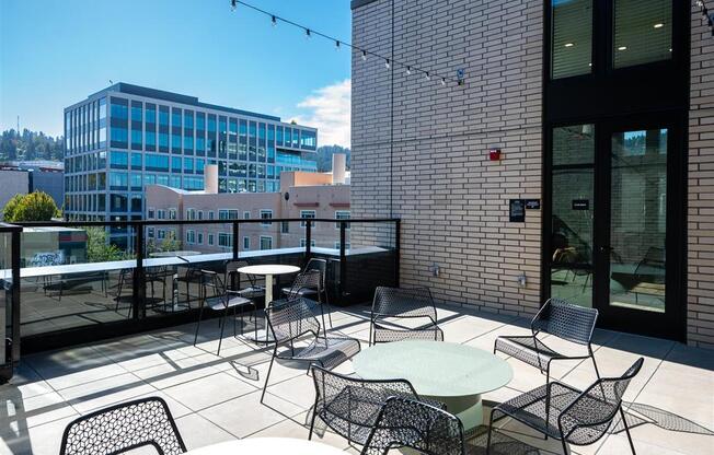 a rooftop patio with tables and chairs and a city in the background