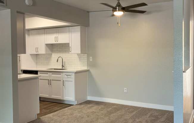 an empty living room and kitchen with a ceiling fan