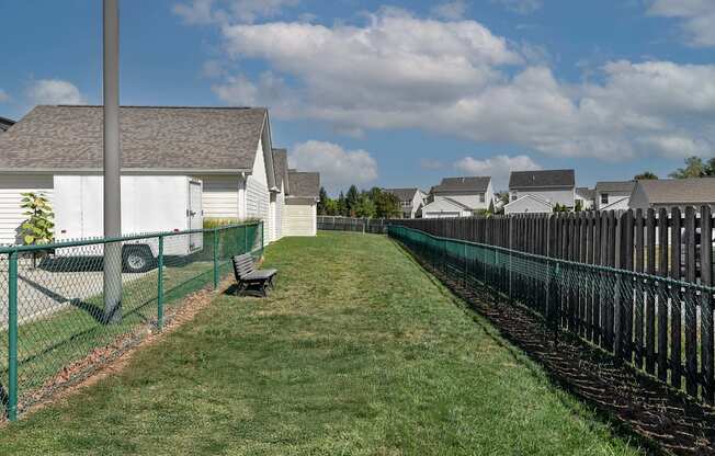 A long green fence runs down the middle of a grassy area.