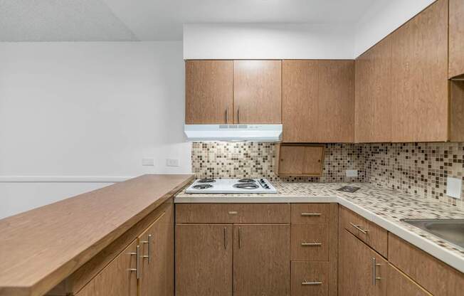 A kitchen with wooden cabinets and a white stove top oven at The Phoenix Apartments on 6th Avenue, Phoenix