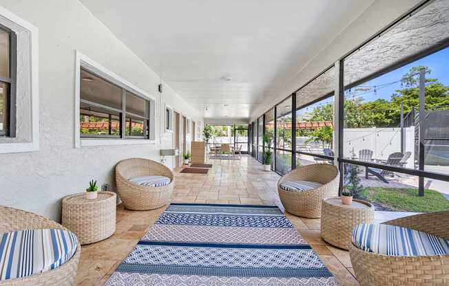 A long white covered walkway with wicker chairs and tables on either side.