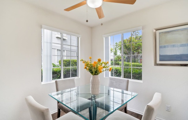 a dining room with a glass table and chairs and windows