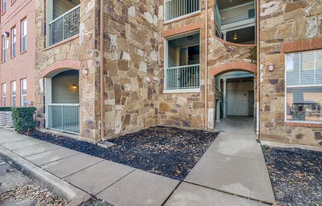 an empty sidewalk in front of a brick apartment building