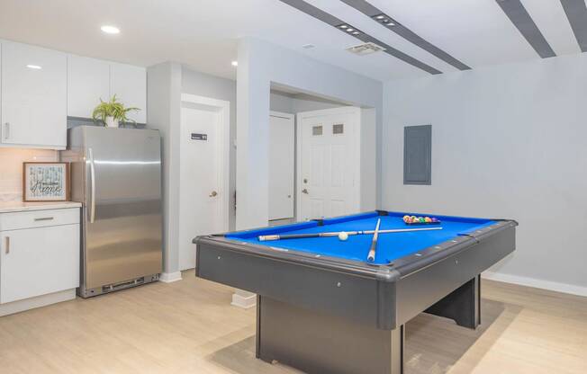 a games room with a pool table and a refrigerator