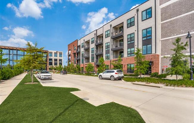 A modern apartment complex with cars parked in front.