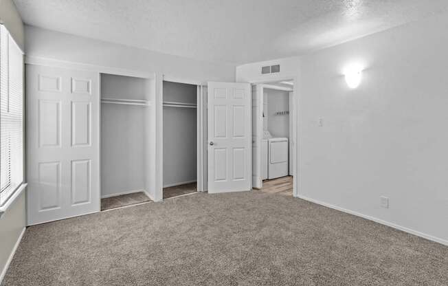 A room with white walls and carpeted floor with four doors.