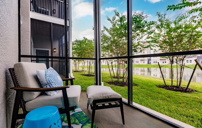 a balcony with a couch and a chair and a view of the grass