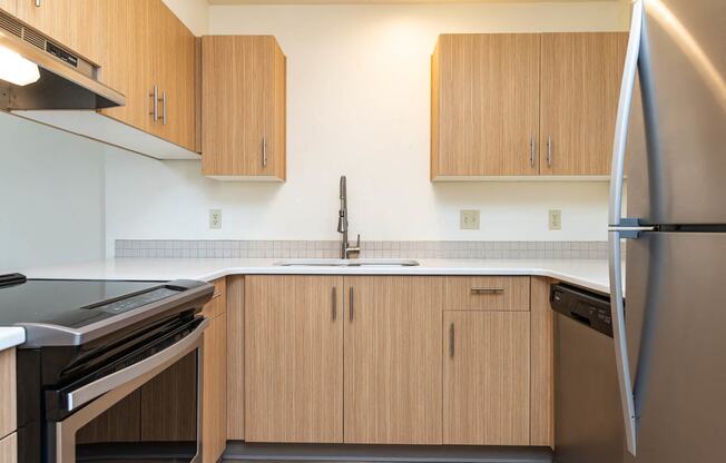 Kitchen with stainless steel refrigerator, black stove and wood cabinetry