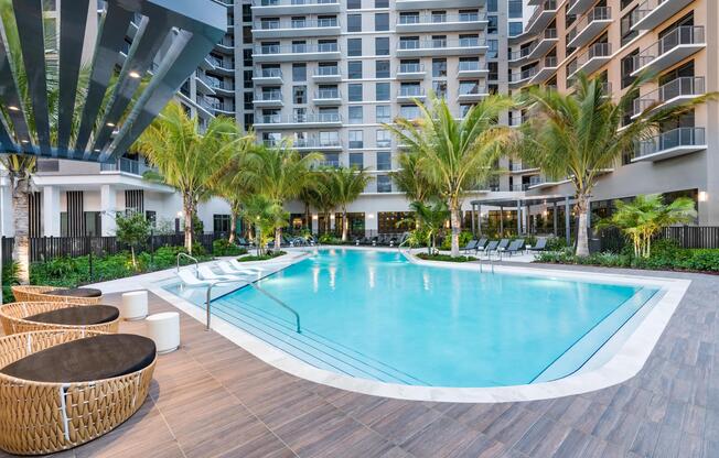 Resort-style pool design with curved entry steps, wood-look decking, and layered palms— the epitome of Miami living.