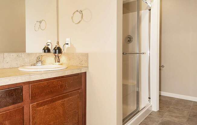 A bathroom with a sink, mirror, and tiled floor at The Landing Apartments and Townhomes, Oregon, 97045