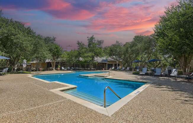 a swimming pool at a resort with trees and a pink sky