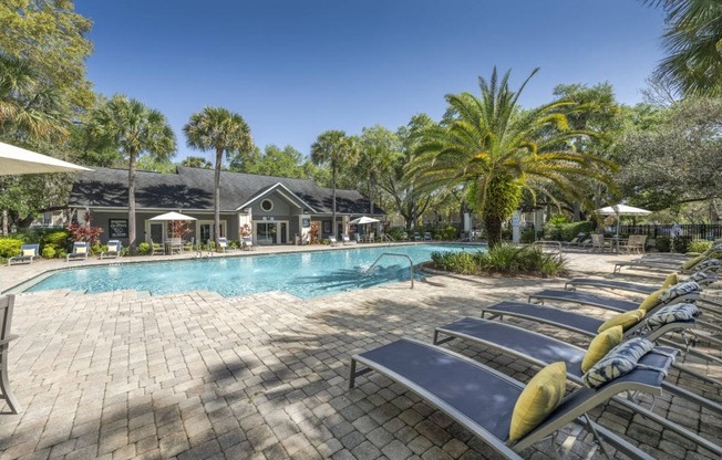 A pool area with sun loungers and a building in the background.