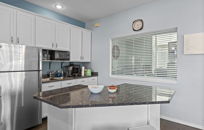 a kitchen with a granite counter top and a stainless steel refrigerator