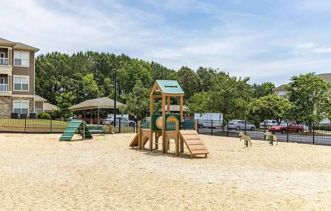 A playground with a wooden structure and a green slide.