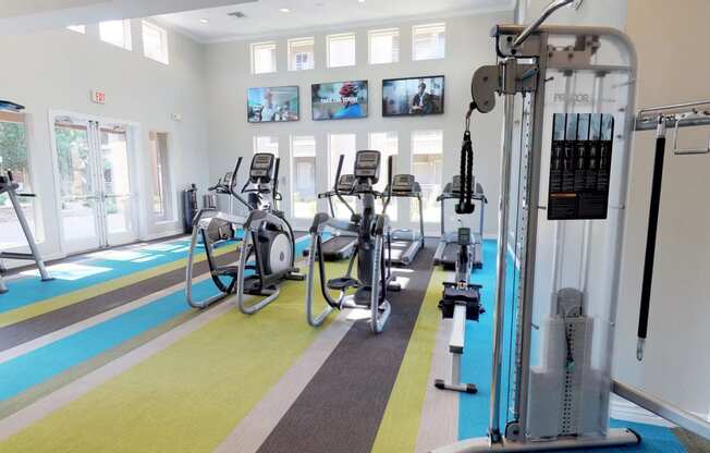 Fitness center with weight machine, stationary bicycles, and large TV's