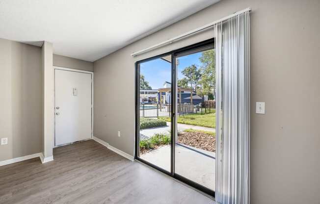 an empty living room with sliding glass doors to a yard