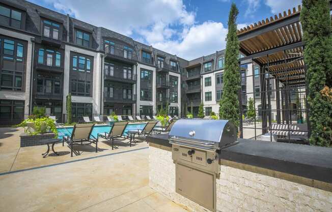 a patio with a grill and a pool in front of an apartment building