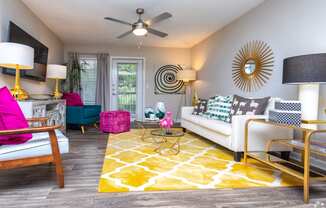 a living room with a ceiling fan and a yellow rug