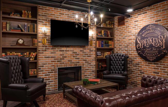 A cozy lounge with exposed brick walls, featuring two leather armchairs, a wooden coffee table, and a fireplace. Thereâs a flat-screen TV mounted on the wall, surrounded by shelves filled with books. The decor includes a chandelier and a sign reading âMidnight Club Speakeasy.â A warm and inviting atmosphere.