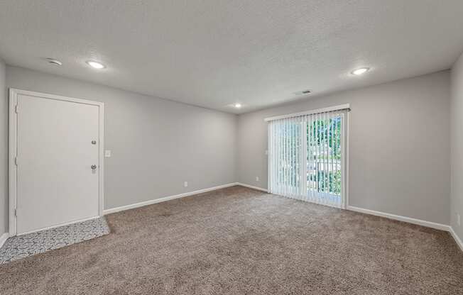 an empty living room with a window and a door to a closet