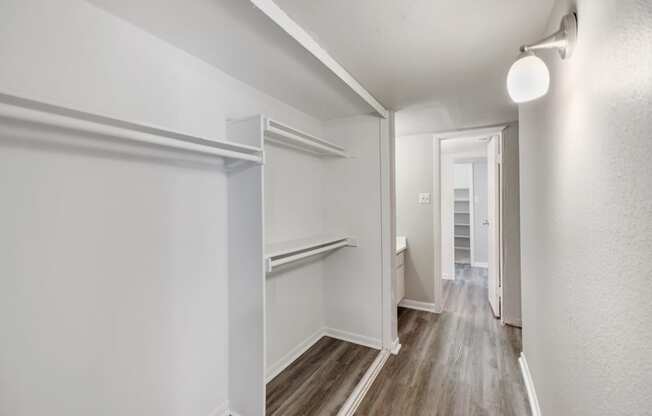 an empty room with white walls and wood floors and a hallway with a white door