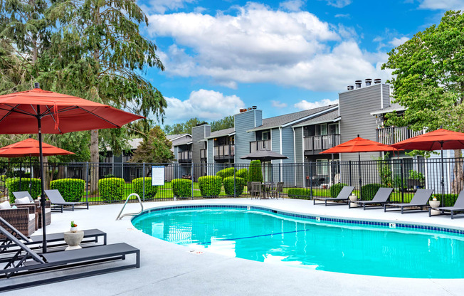 a swimming pool with umbrellas in front of apartment buildings