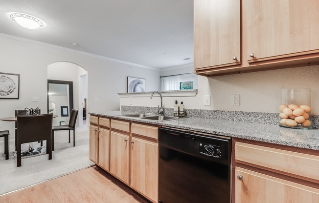 A kitchen with wooden cabinets and a black dishwasher.Plantation Crossing, Lafayette, LA, 70508