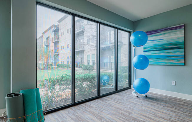 an empty living room with large windows and blue balloons