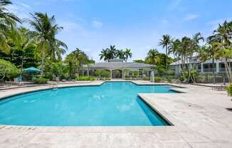 a swimming pool with palm trees and a building in the background