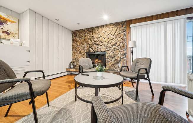 A living room with a stone fireplace and a grey rug.