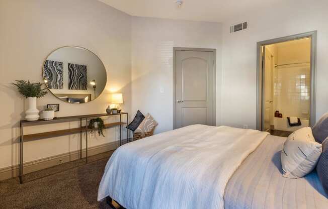 a bedroom with a large white bed and a mirror at Mirasol Apartments, Las Vegas