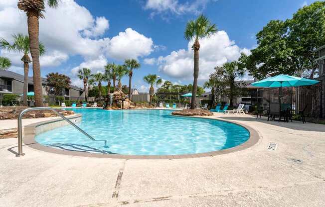 A round swimming pool surrounded by palm trees and lounge chairs.