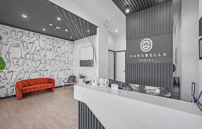 A dental office with a white reception desk and a red couch.