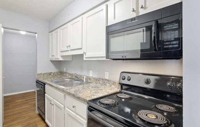 Kitchen with white cabinets and black appliances and a sink  at Governors House, Huntsville, Alabama