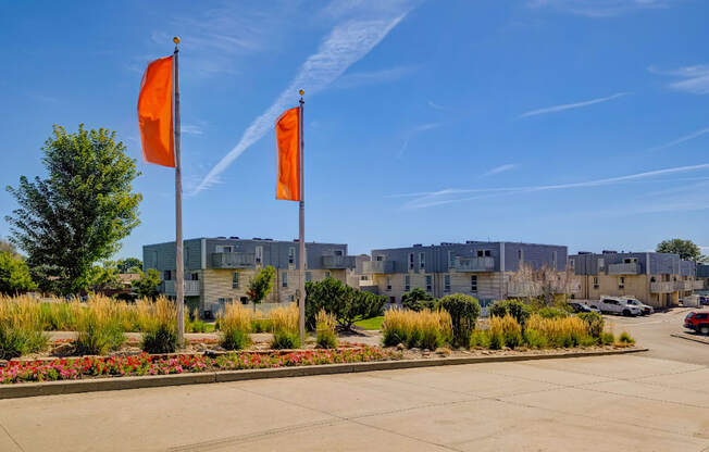 Two orange flags on a pole in front of a building.