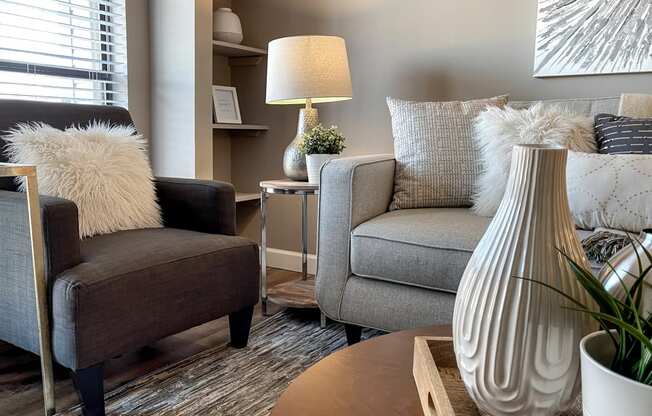 a living room with two chairs and a table and a vase