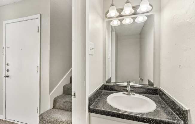 a bathroom with a sink and a mirror and a staircase