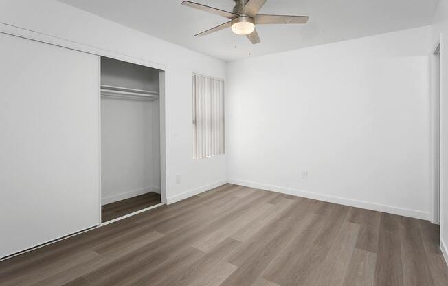 A room with a ceiling fan and a wooden floor.
